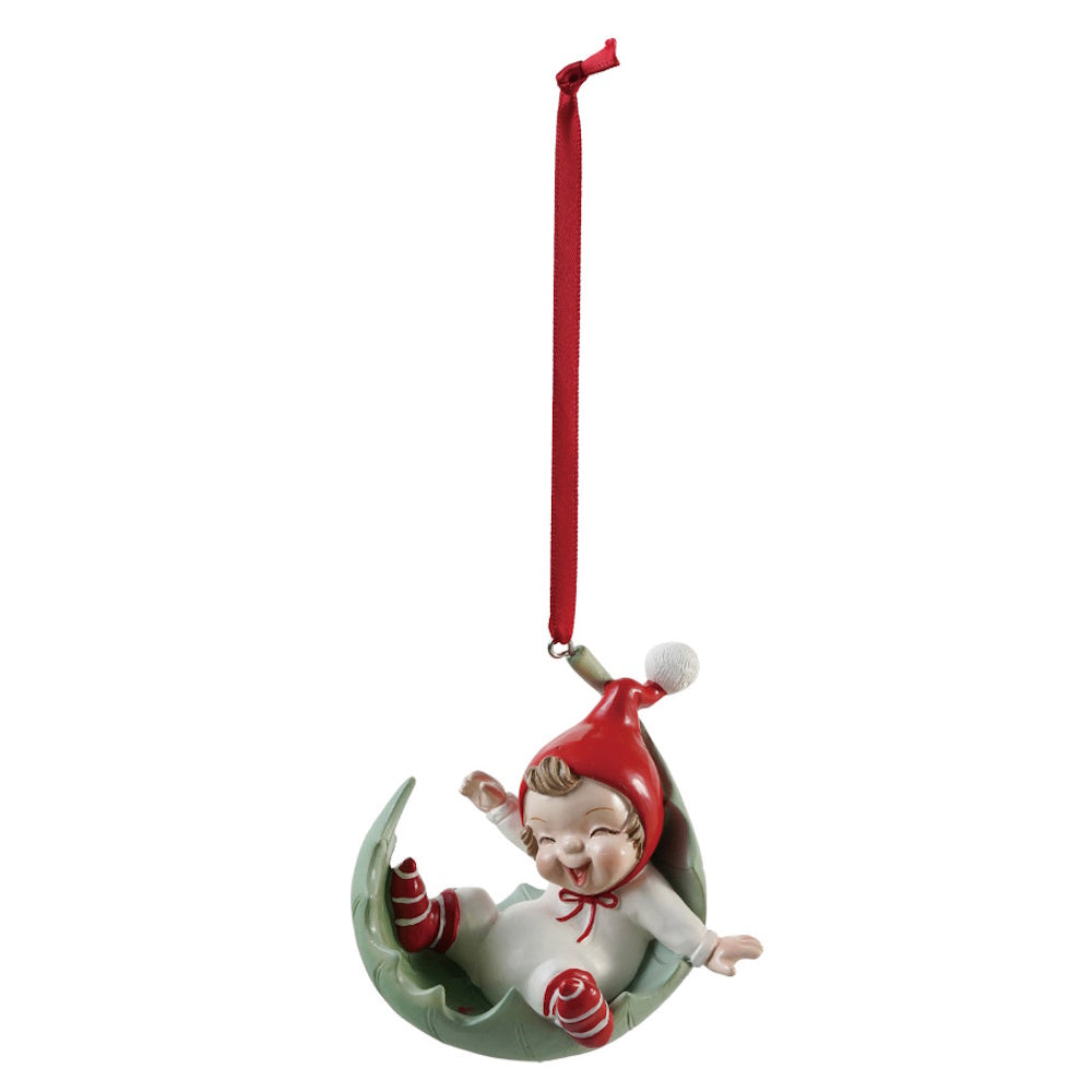 Resin elf ornament resting in a green leaf-shaped cradle with a red ribbon.