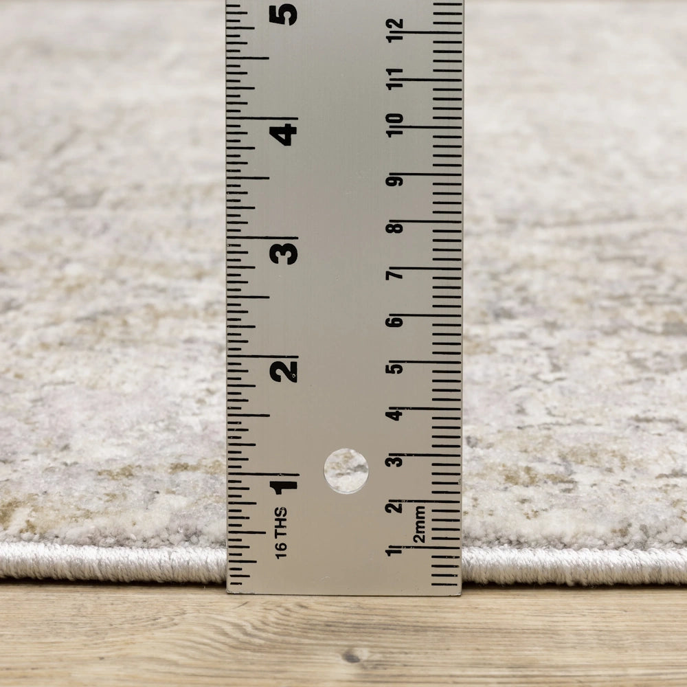 Close-up of the gray, taupe, and cream area rug with a ruler to show pile height.