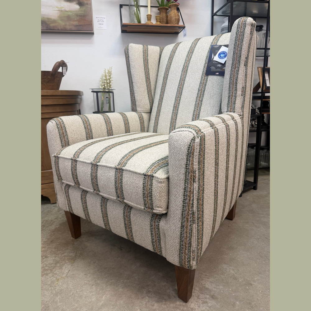 Upholstered wingback accent chair featuring a neutral, green, and brown vertical stripe pattern and tapered wooden legs.