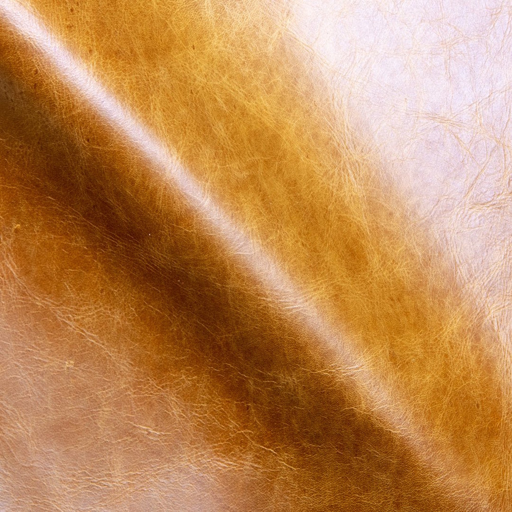 Close-up of smooth, amber-colored leather with natural grain and a subtle sheen.