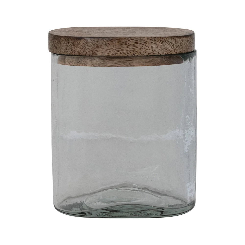 Hand-blown clear glass storage jar with a natural mango wood lid on a white background.