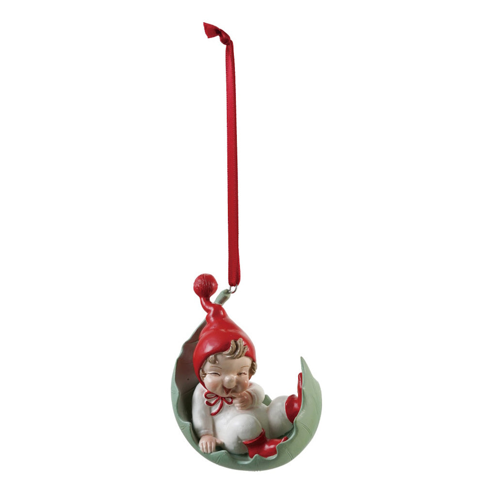 Resin elf ornament resting in a green leaf-shaped cradle with a red ribbon.