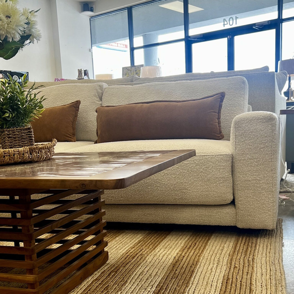 Cream textured sofa with brown lumbar cushions behind a slatted wooden coffee table.