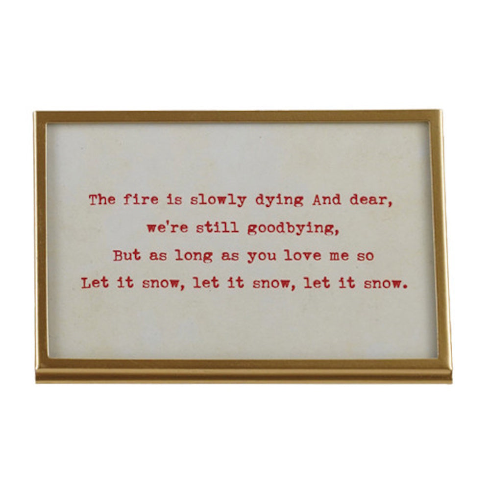Gold framed sign displaying typed red text with the holiday lyrics, "Let it snow, let it snow, let it snow."