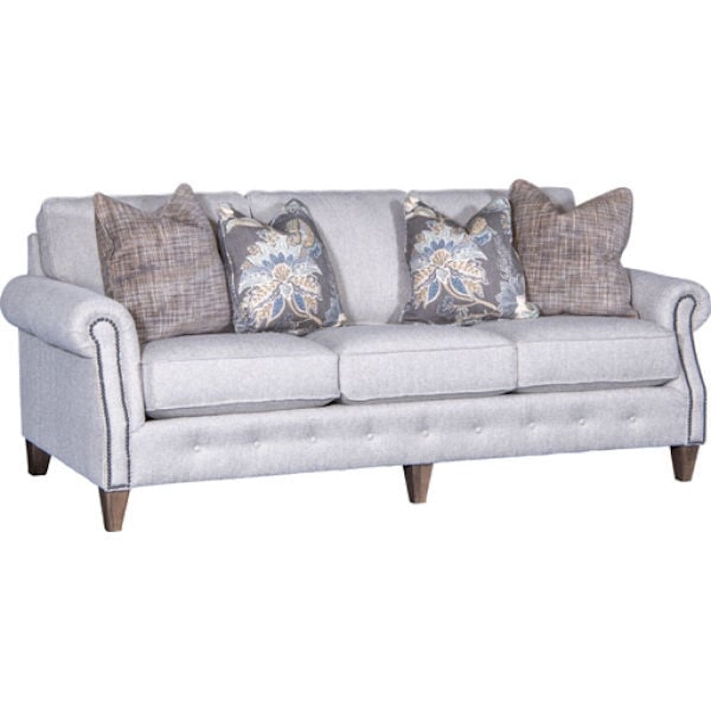 Light grey three-cushion sofa with rolled arms, nailhead trim, wooden legs, and four throw pillows.
