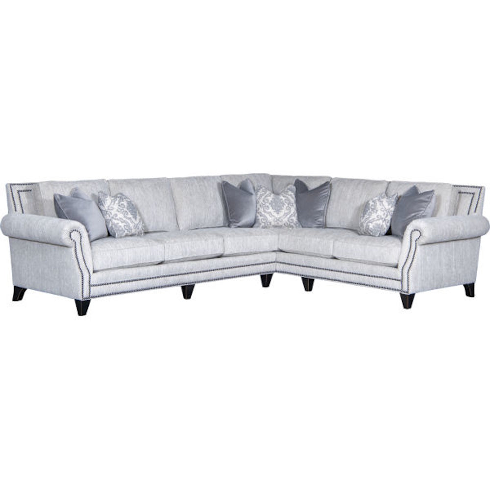 Light gray sectional sofa with nailhead trim detailing and decorative gray throw pillows.