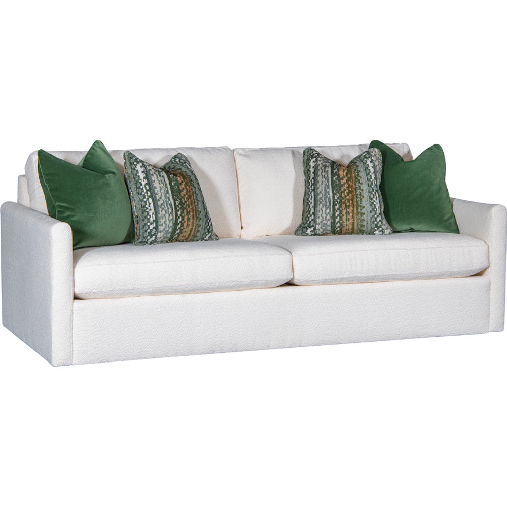 White upholstered sofa with green velvet pillows and patterned accent cushions against a plain background.