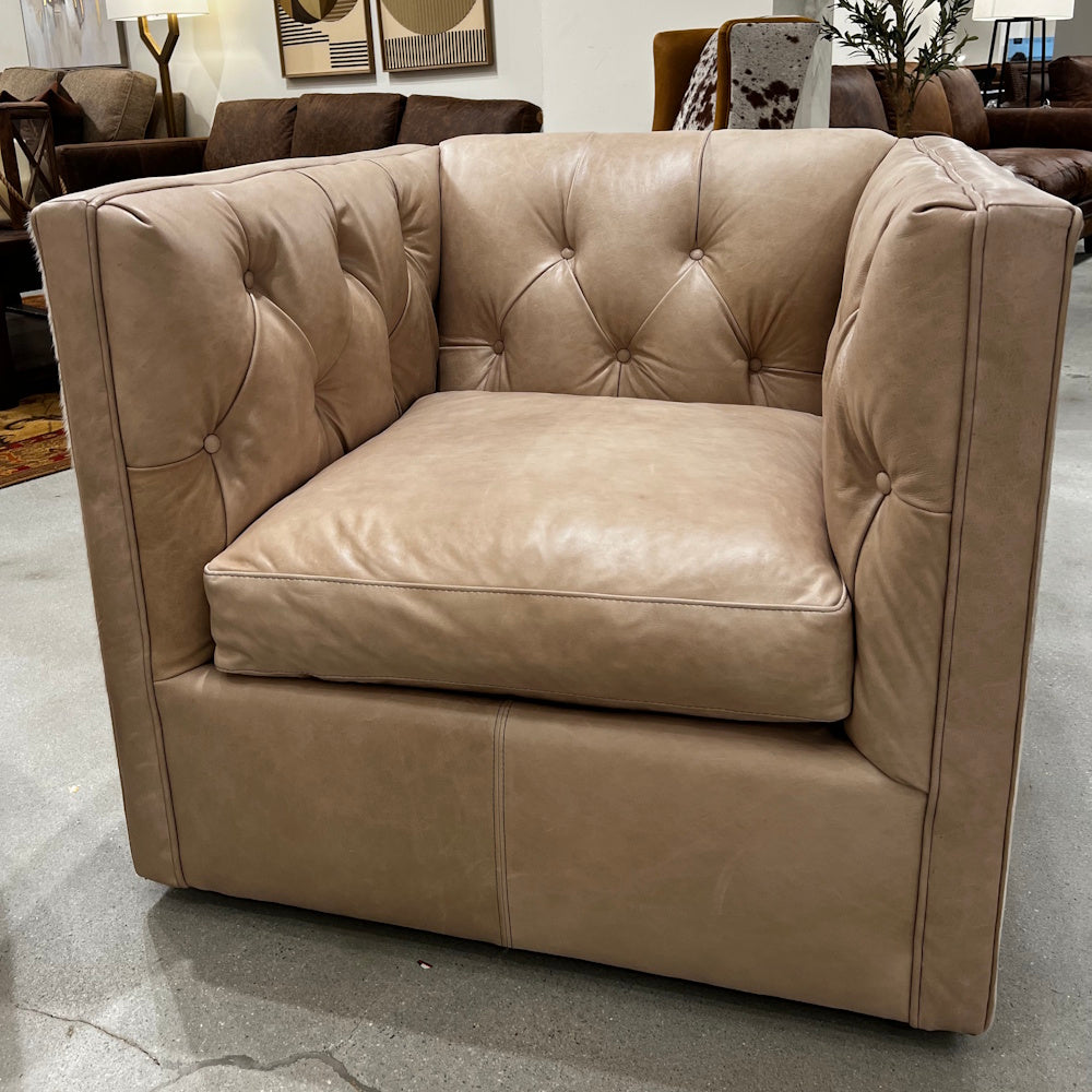 Tufted beige leather armchair in a showroom setup.