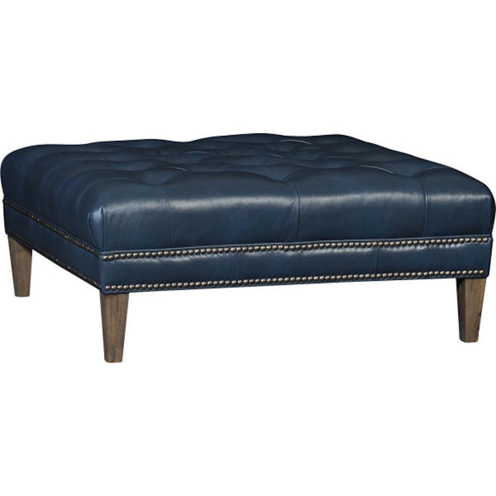 Tufted navy blue leather ottoman with double nailhead trim and wooden legs.