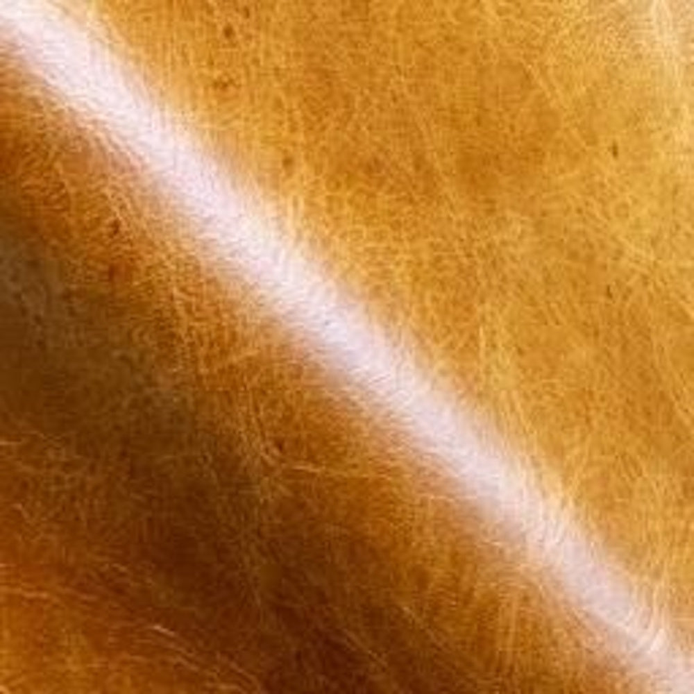 Close-up macro texture of distressed cognac amber leather upholstery.