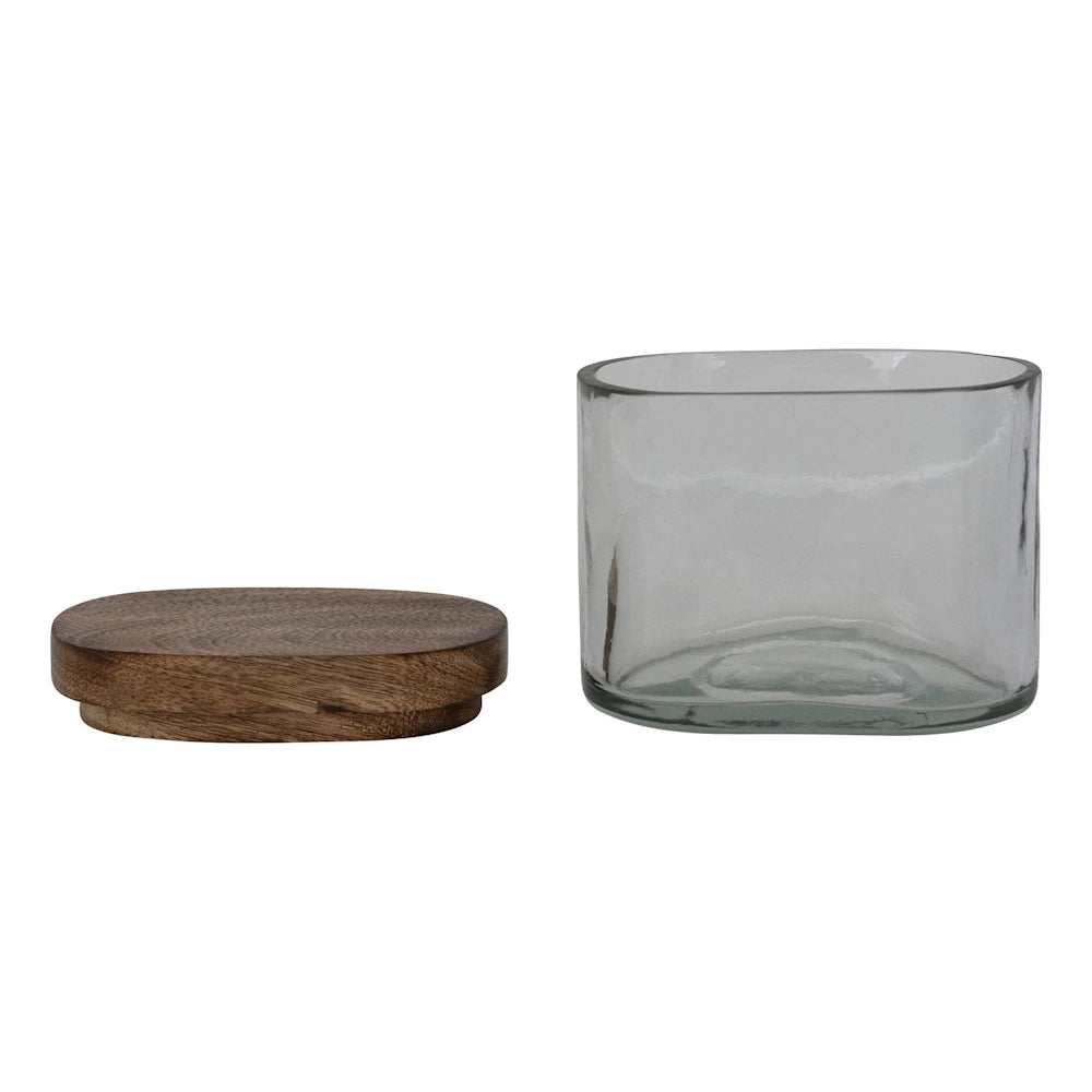 Hand-blown clear glass storage jar with a natural mango wood lid, isolated on a white background for home decor.
