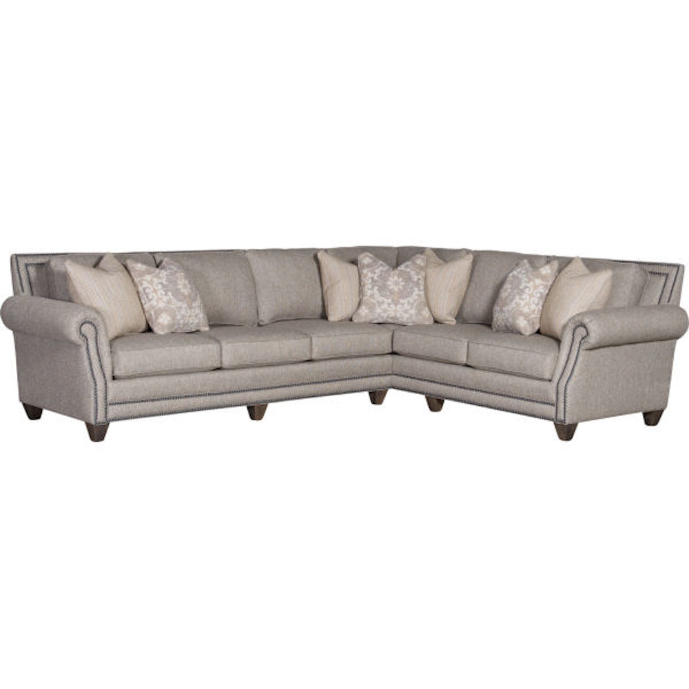 Beige sectional sofa with rolled arms, nailhead trim, and throw pillows.