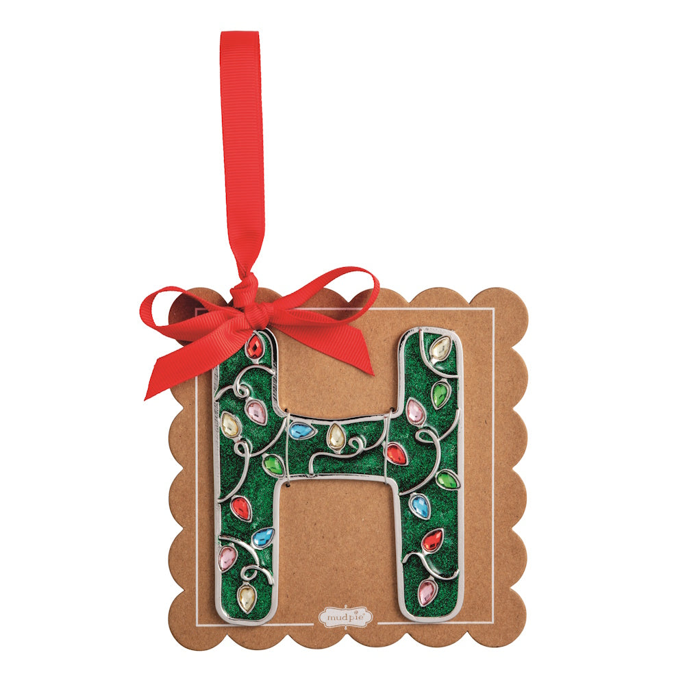 Sparkly green Christmas initial ornament letter H on a scalloped brown card with a red hanging ribbon.