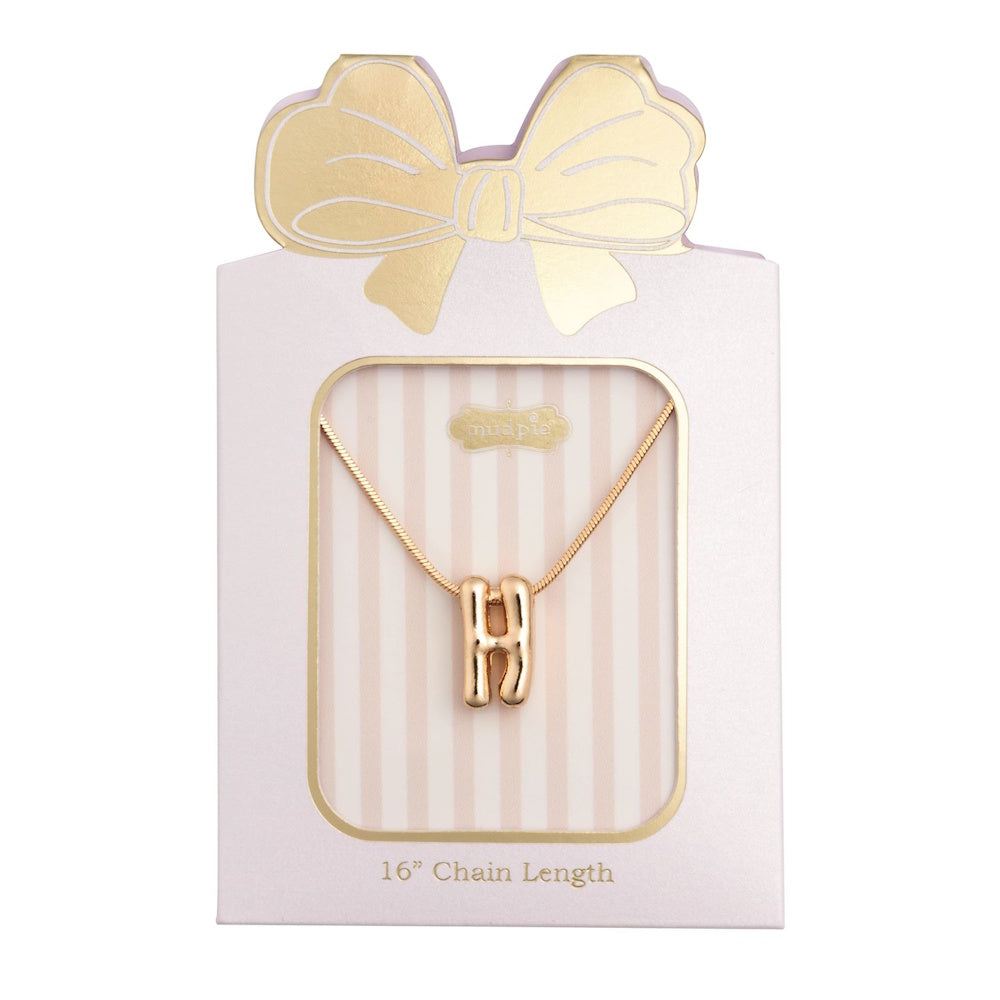 Gold initial "H" pendant necklace packaged in a pink box with a gold bow design.