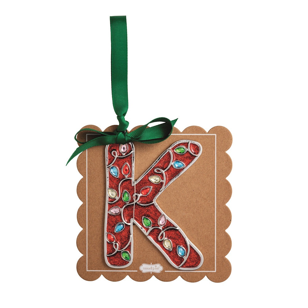 Sparkly red Christmas initial ornament letter K mounted on a scalloped brown card with a green hanging ribbon.