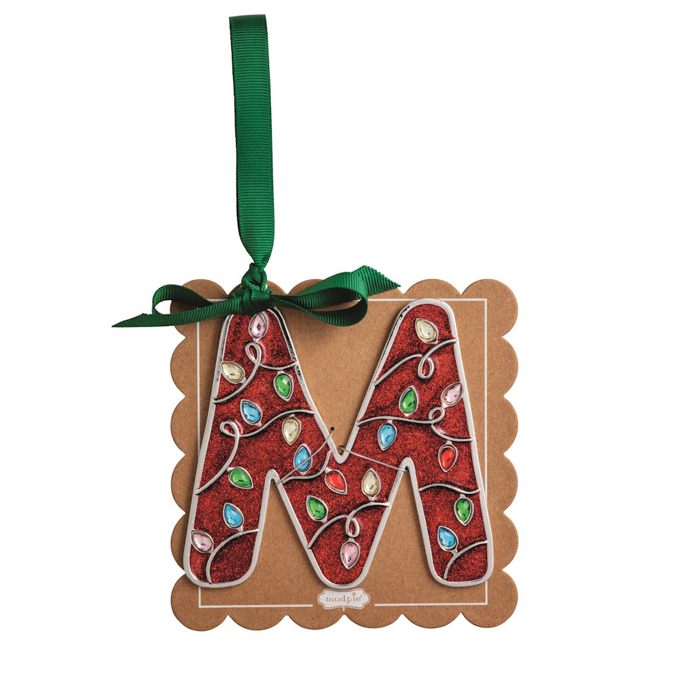 Sparkly red Christmas initial ornament letter M mounted on a scalloped brown card with a green hanging ribbon.