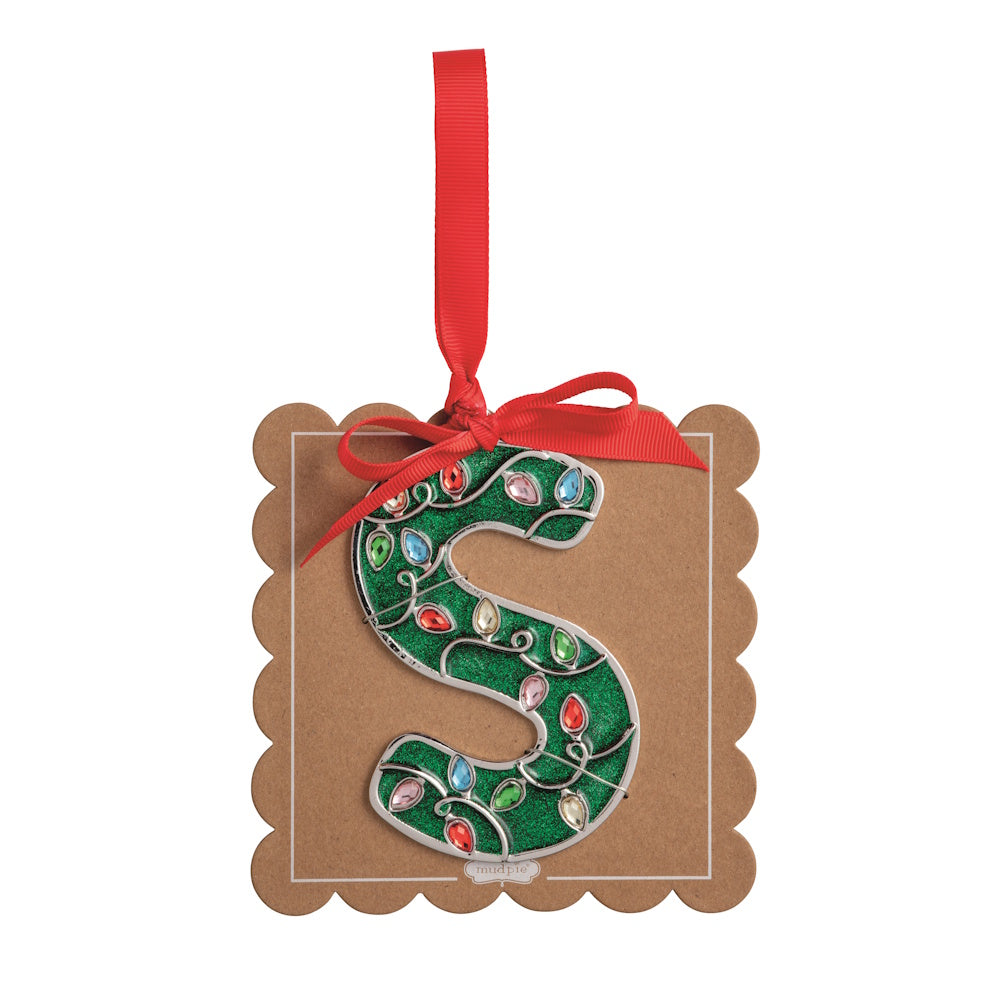 Sparkly green Christmas initial ornament letter S on a scalloped brown card with a red hanging ribbon.