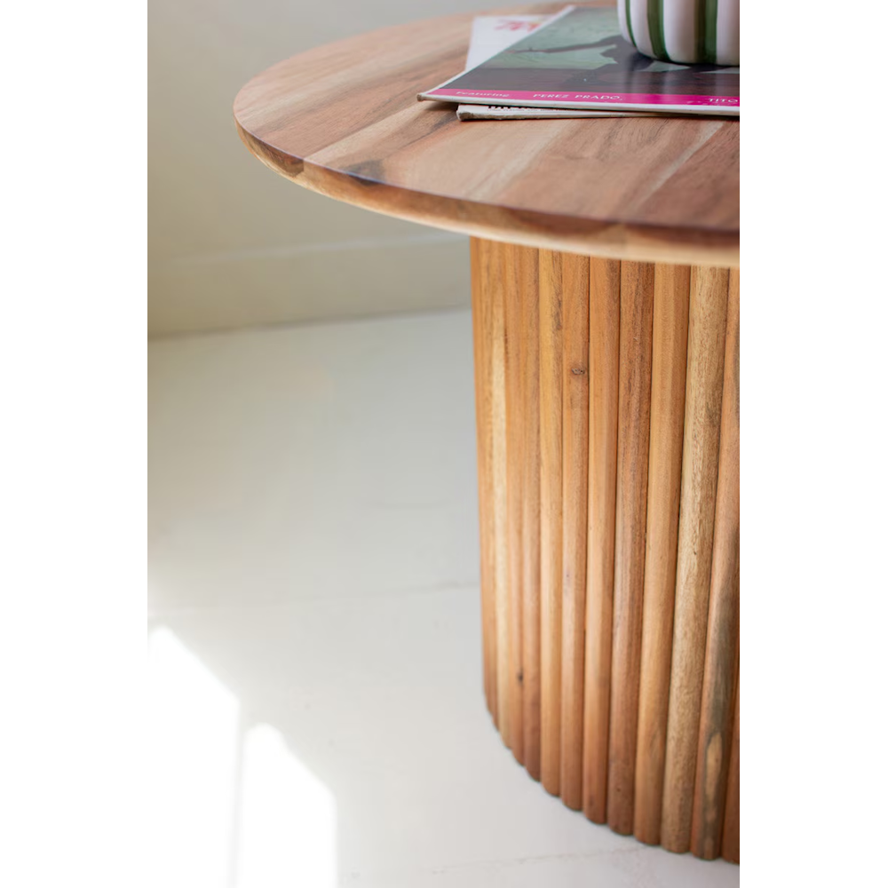 Close-up view of a natural acacia wood accent table showing the smooth tabletop and ribbed tambour base.