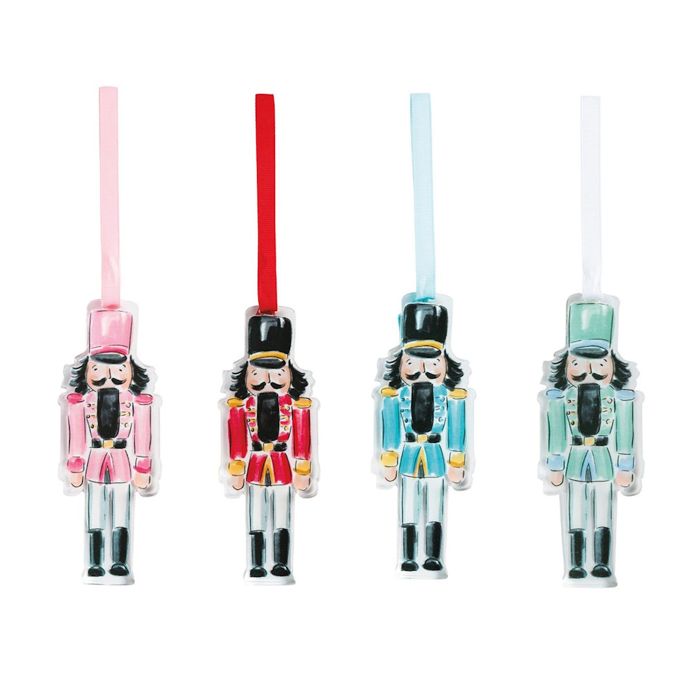 Four acrylic nutcracker ornaments in pink, red, blue, and green with hanging ribbons.