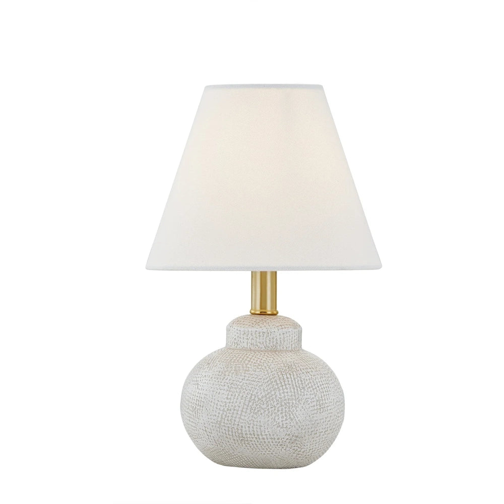 White textured ceramic table lamp with tapered shade, brass accent and round base for modern decor.