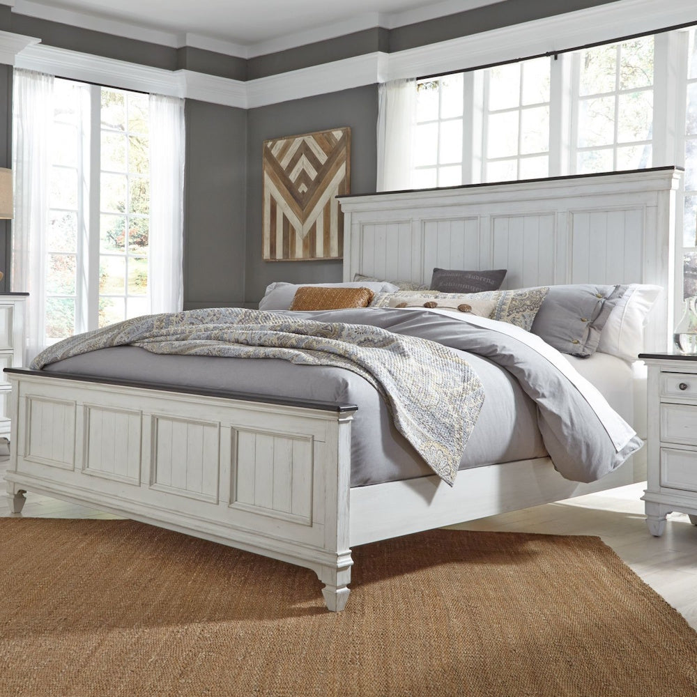 Distressed white king panel bed styled in a modern bedroom with neutral bedding and a woven rug.
