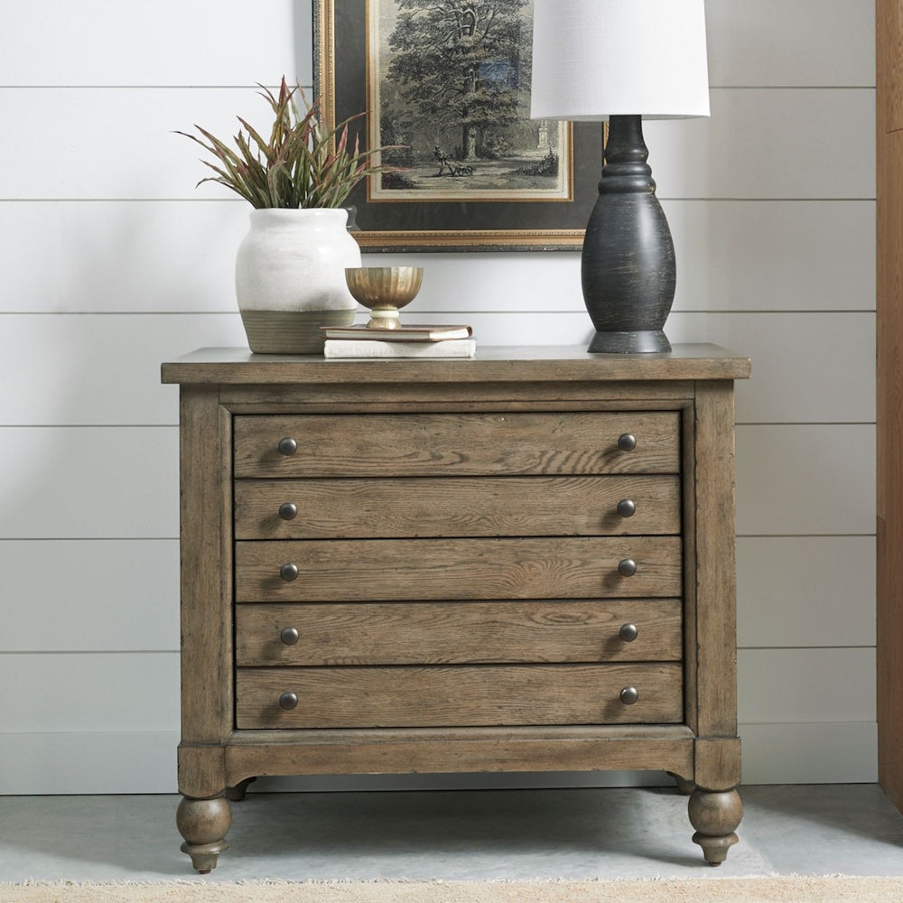 Wooden lateral file cabinet styled in a room with a table lamp, plant, and framed art above.