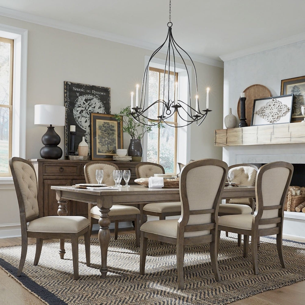 Rustic dining room set with a wooden table and six upholstered chairs under a black chandelier.