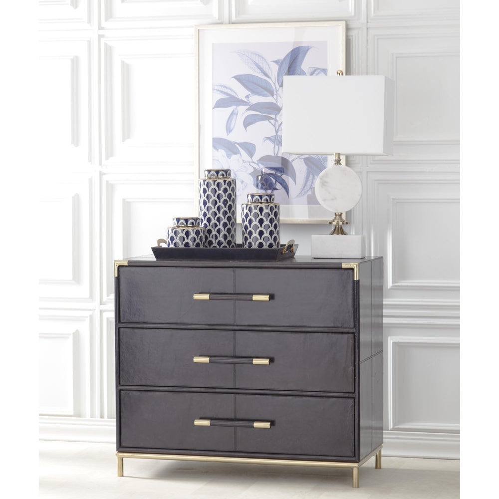 Arabescato white marble lamp on a black three-drawer chest with blue patterned jars and botanical wall art.