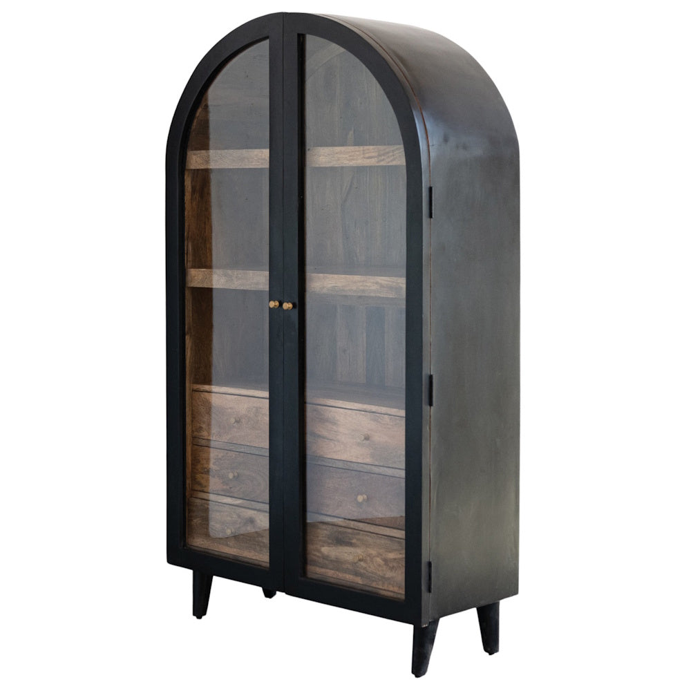 Arched black metal cabinet with glass doors, wood interior shelves, and bottom drawers on a white background.