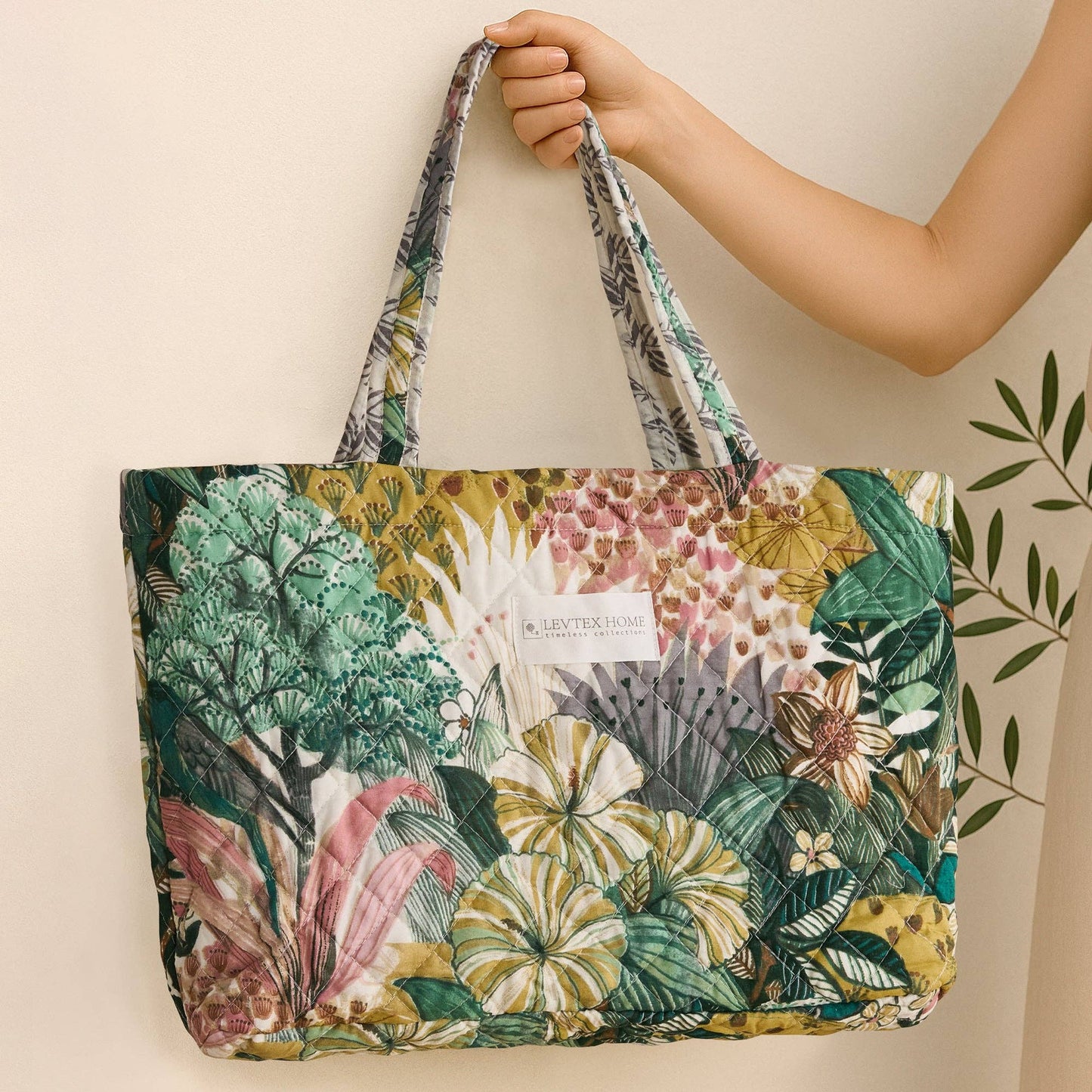 Quilted tote bag with a tropical botanical print in green, pink, and gold by Levtex Home.
