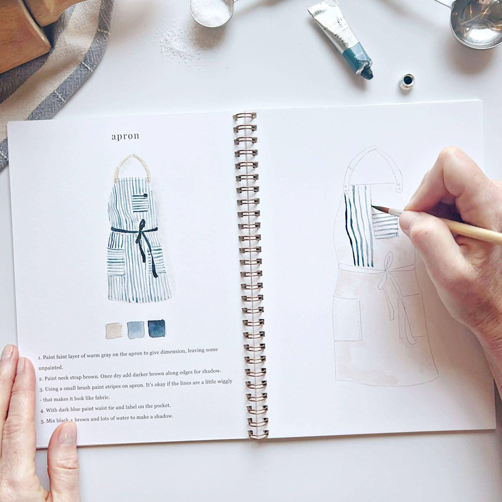 Watercolor apron tutorial in workbook with hand painting blue stripes.
