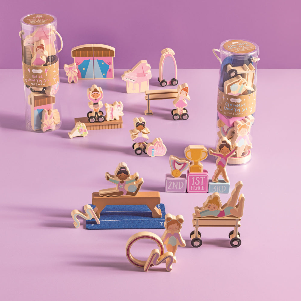 Wooden ballet and gymnastics toy set featuring dancers, balance beams, and trophies on a purple background.