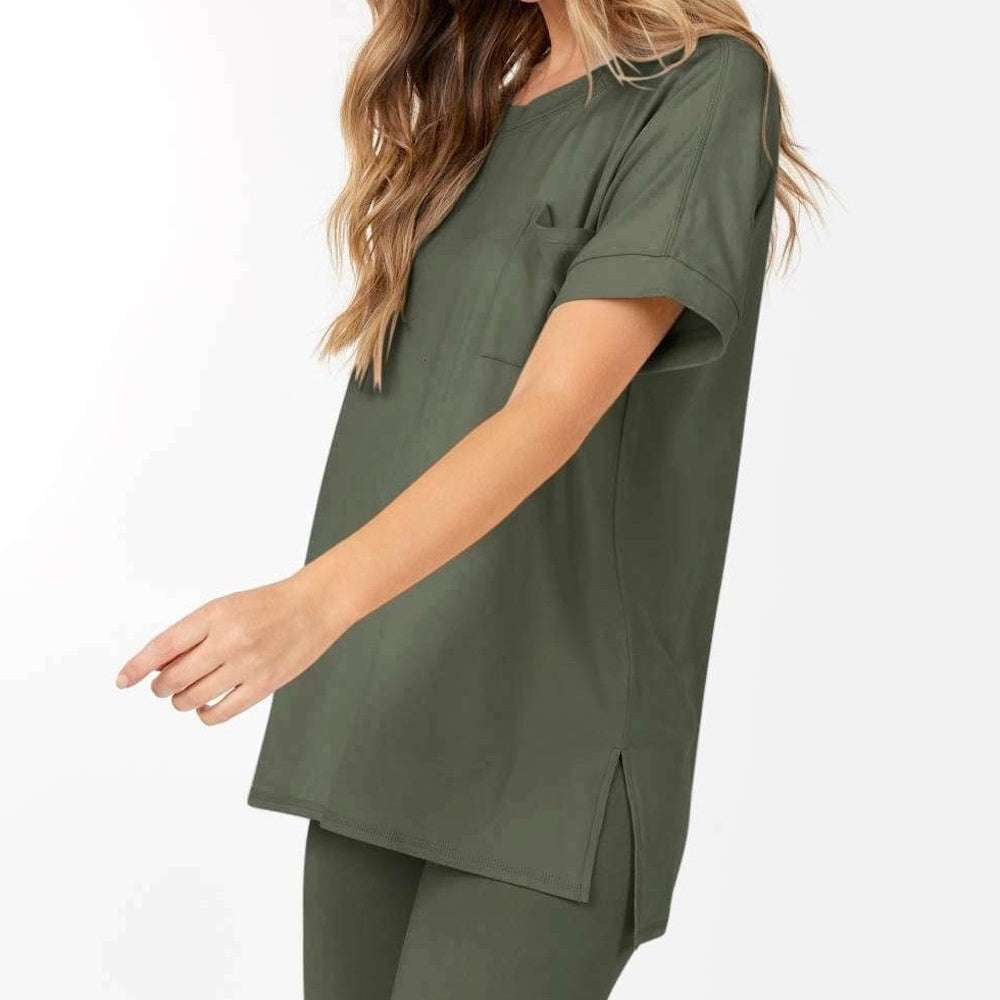 Woman wearing a loose olive green short-sleeve top with a chest pocket and side slits, side view.
