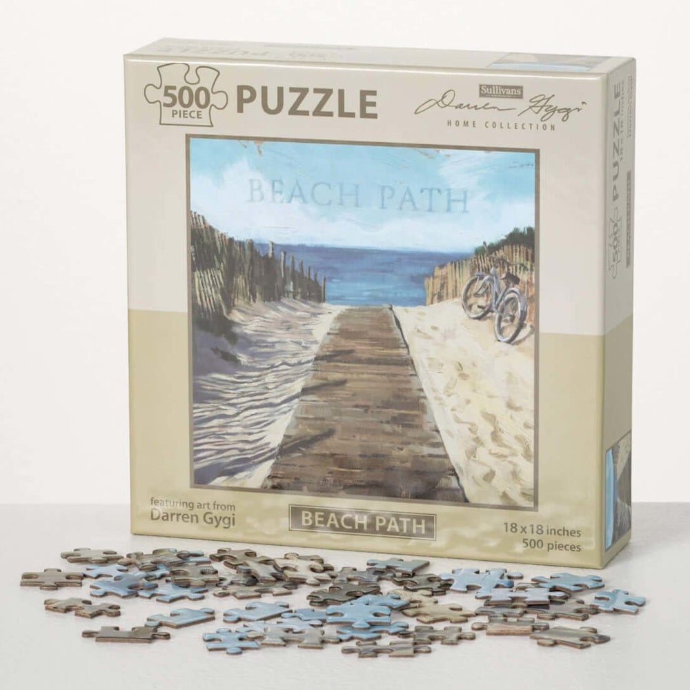 A 500-piece "Beach Path" jigsaw puzzle box standing behind a scattered pile of puzzle pieces.
