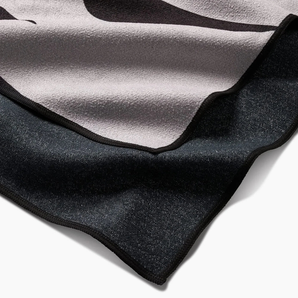 Close-up of a folded black and grey microfiber beach towel with stitched edges.