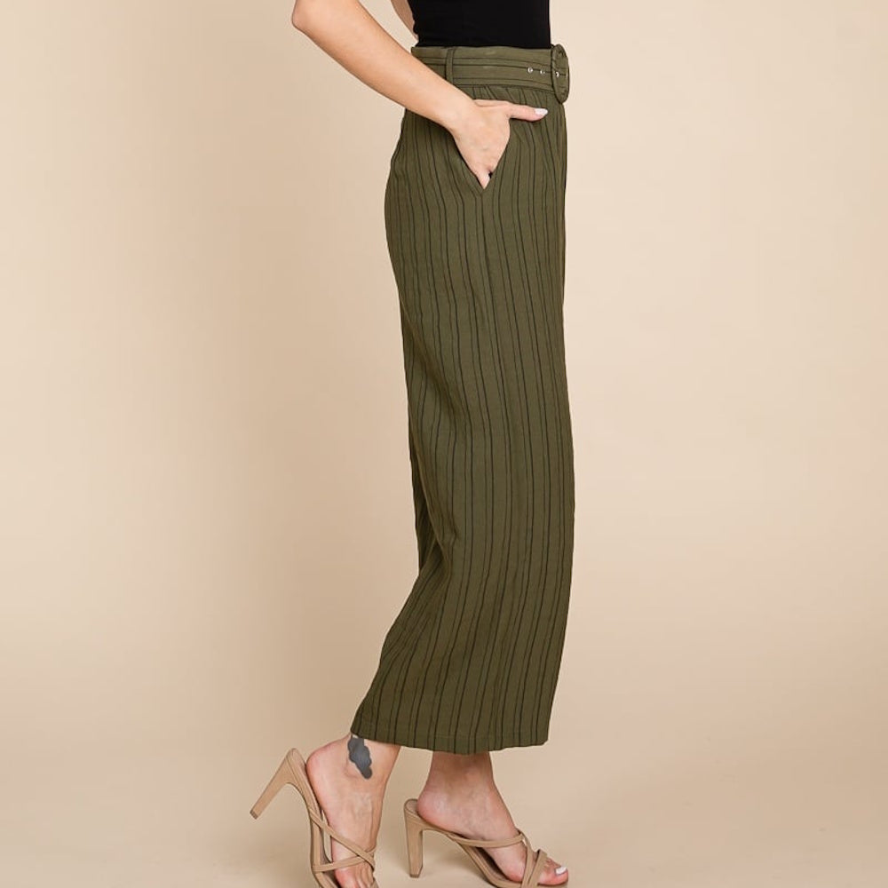 Side profile of a woman wearing olive green striped, high-waisted pants with a belt and beige heels.