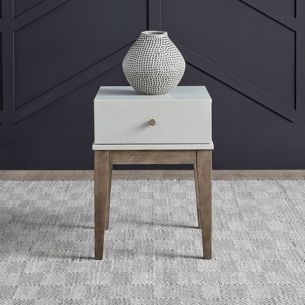 Two-tone chairside table styled with textured vase in modern living room setting.