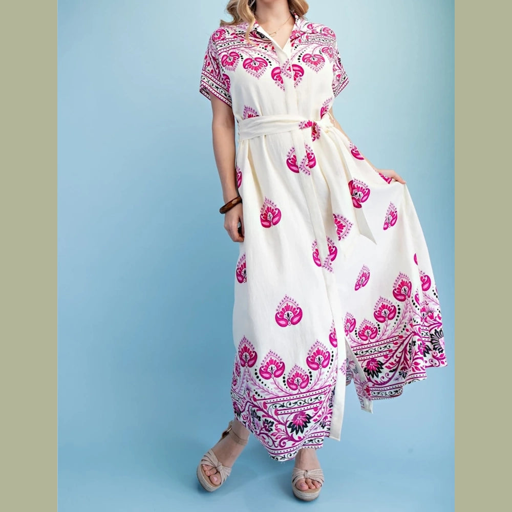 Woman in a white and magenta patterned maxi shirt dress with a waist tie and neutral wedge sandals.