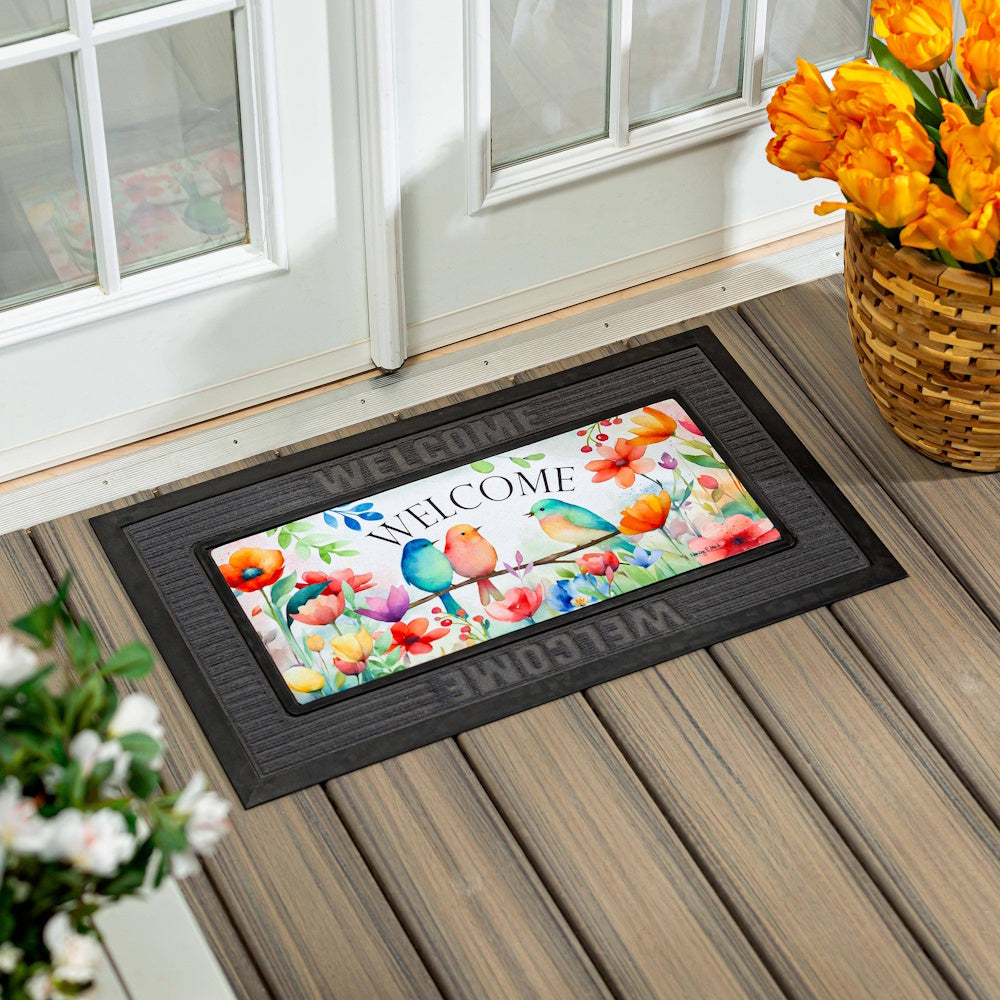 Welcome birds Sassafras switch mat with colorful flowers on a porch.