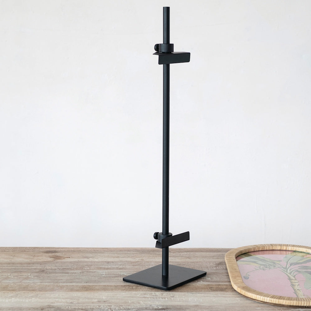 Adjustable black metal tabletop display easel on a rustic wooden table.
