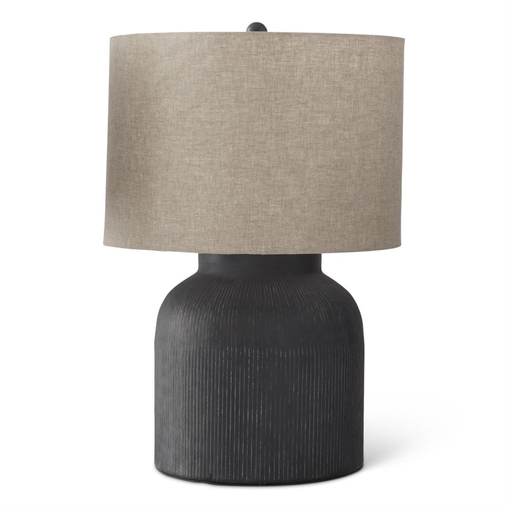 Modern black ceramic table lamp with a textured ribbed base and a neutral tan linen drum shade on white.