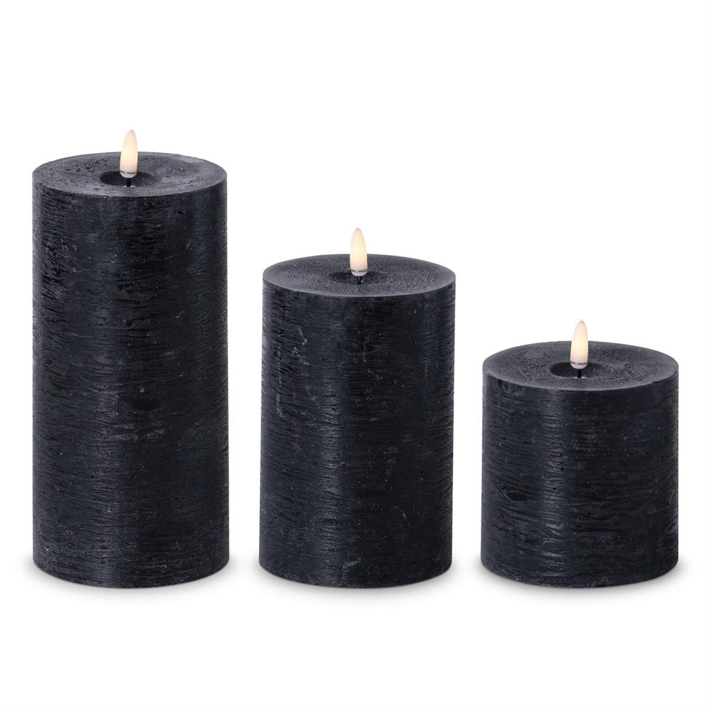 Set of three black flameless LED pillar candles in varying heights with warm glowing flames.