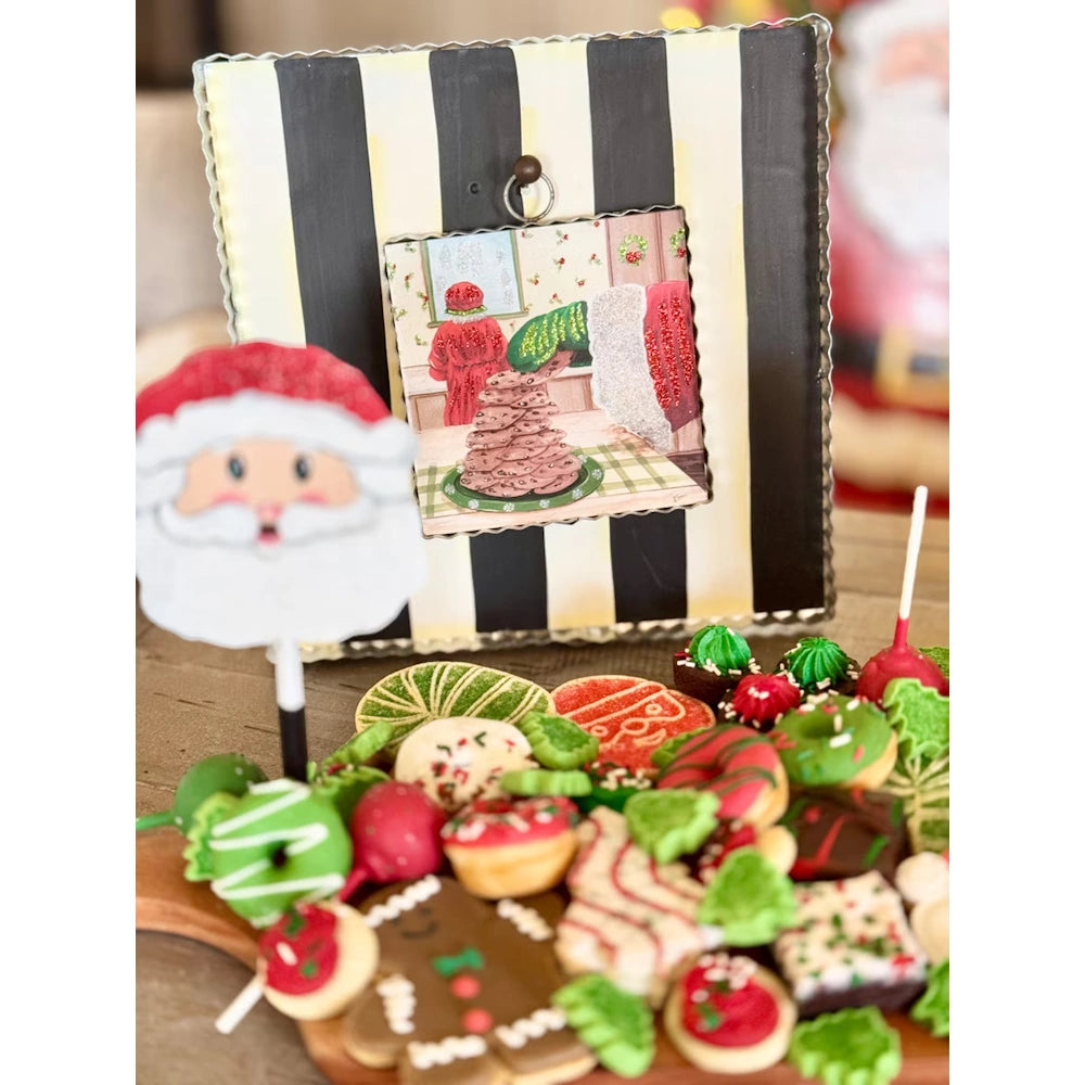 Close-up of a Christmas display board and festive dessert platter featuring holiday cookies and a Santa sign.