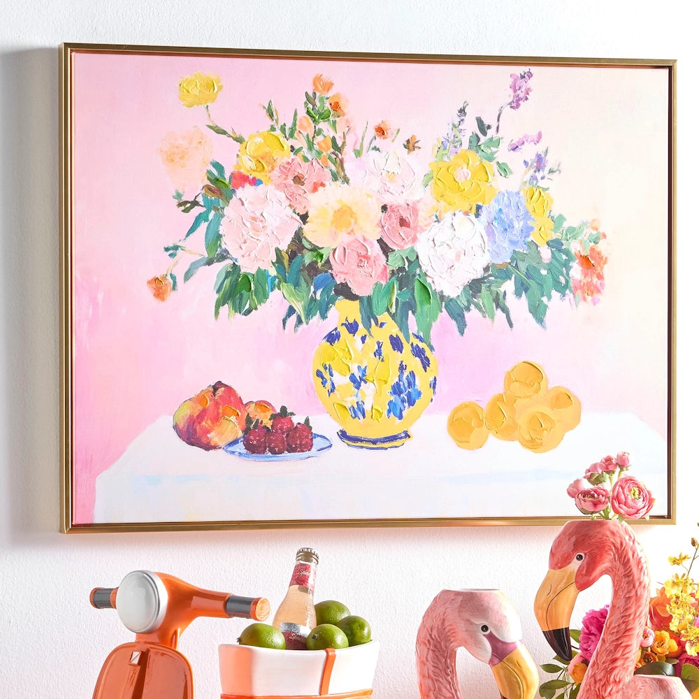 Impressionist painting of colorful flowers in a yellow vase on a pink background, displayed above whimsical decor.