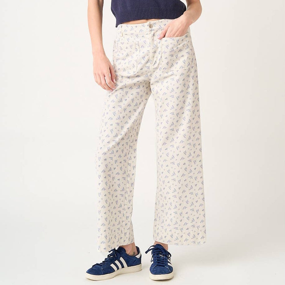 Cream wide-leg pants with a blue ditsy floral print, featuring a high-waist fit and front patch pockets.