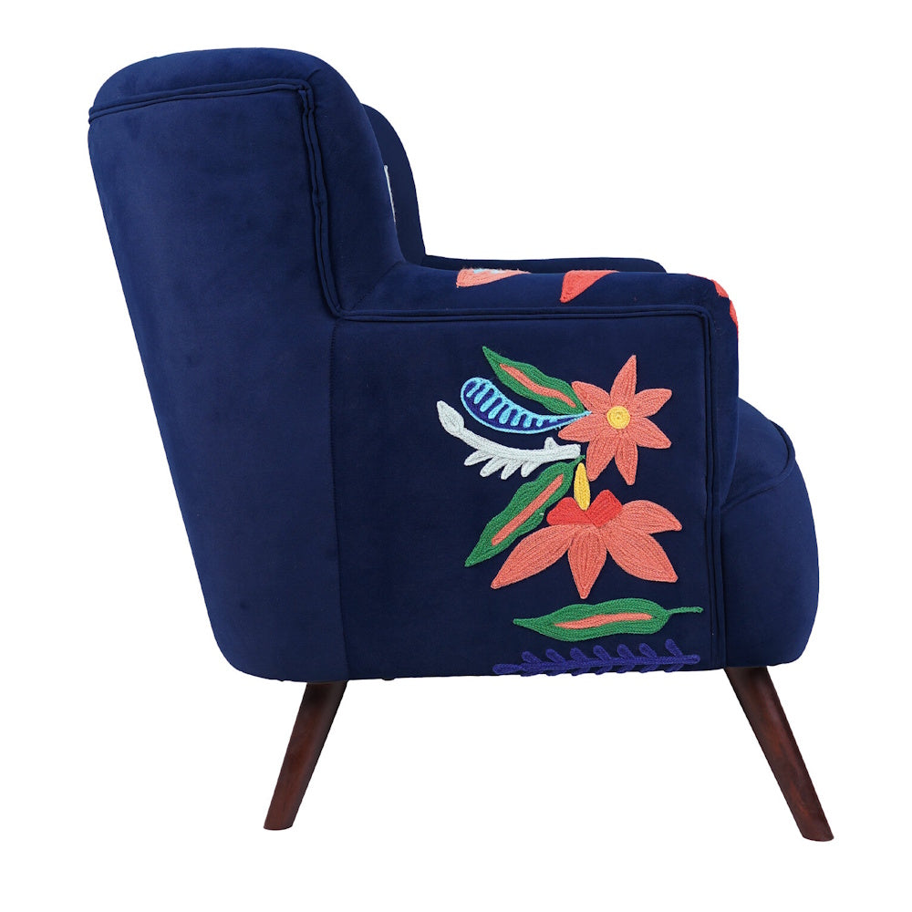 Side view of navy blue accent chair with colorful floral embroidery, upholstered frame and angled wooden legs.