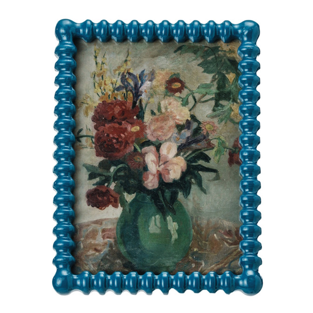 Textured blue picture frame holding a vintage reproduction floral still-life painting.