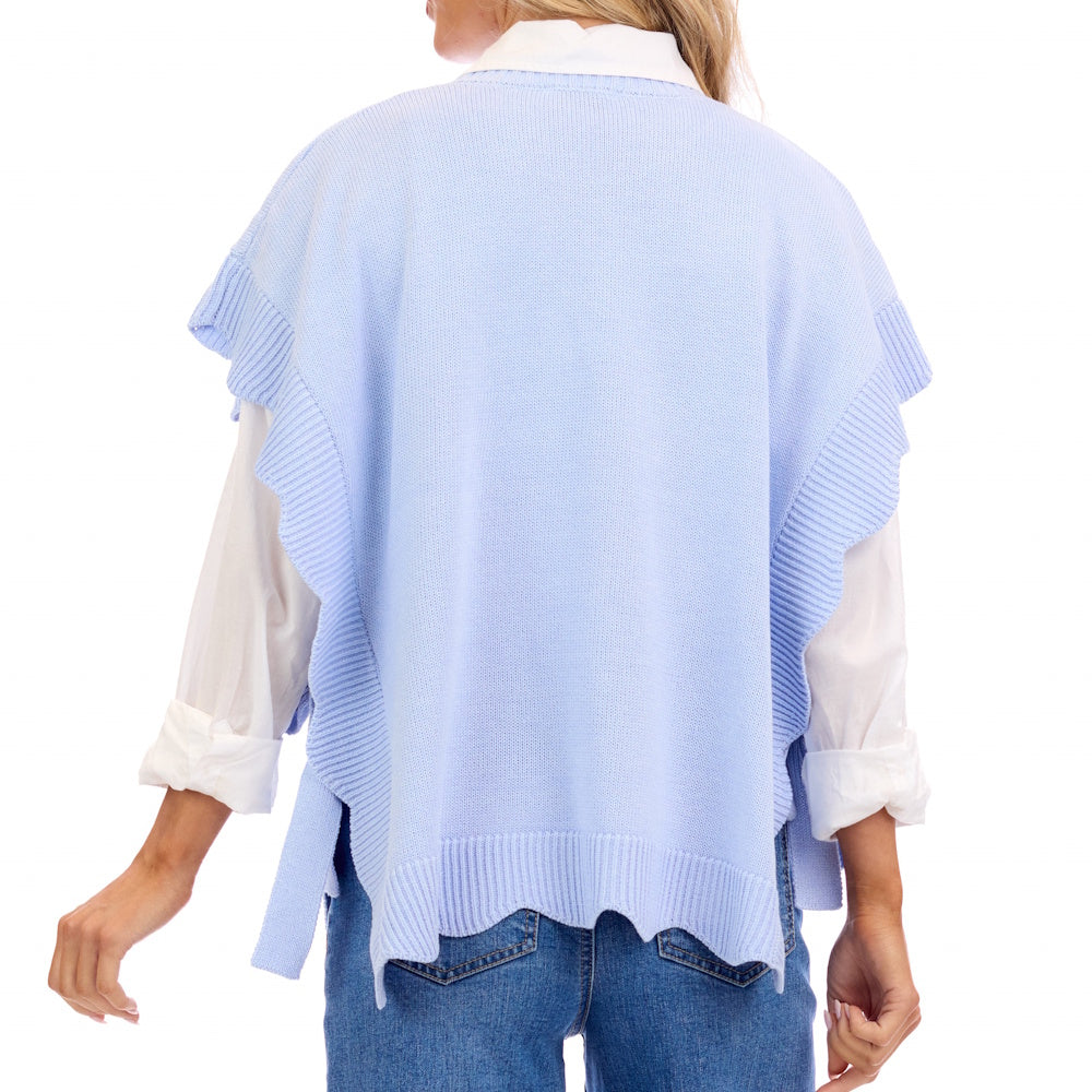 Back view of a person wearing a light blue knit sweater with ruffled edges over a white collared shirt and jeans.