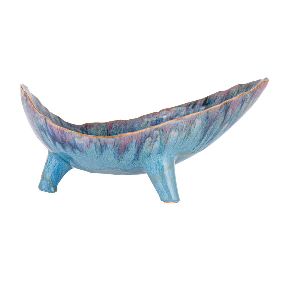 Side view of a blue footed stoneware bowl with an organic wavy rim and reactive glaze on a white background.