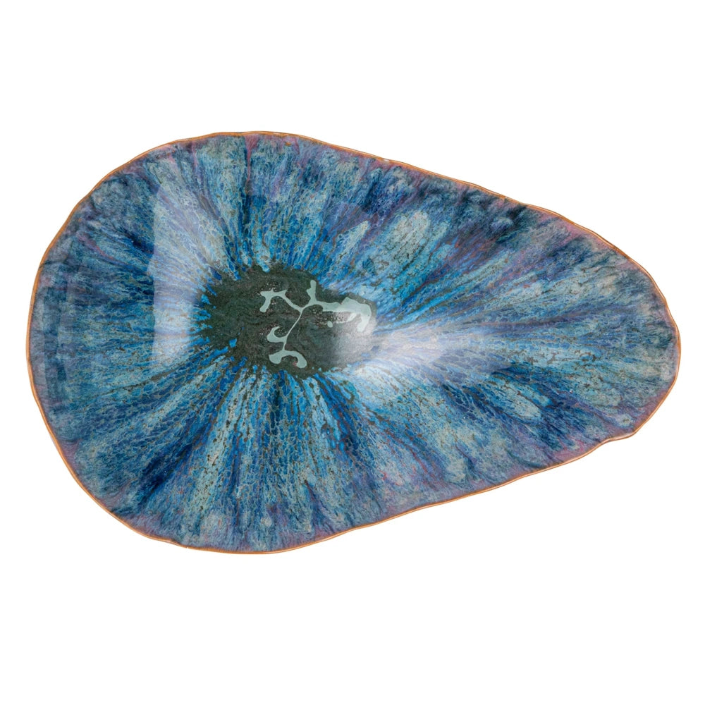 Top-down view of an organic-shaped blue stoneware bowl featuring a reactive sunburst glaze in indigo and turquoise.
